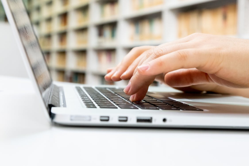 Graduate student typing on a laptop while working on a thesis