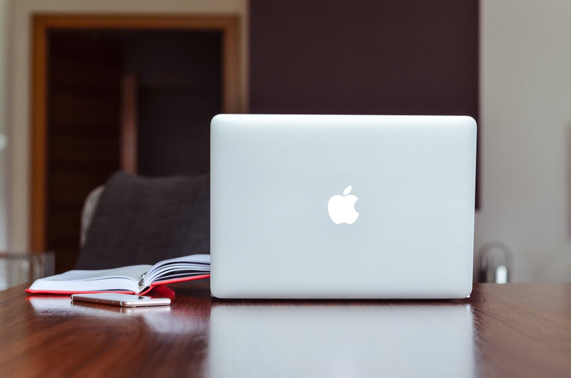 Alt Text: Laptop on a desk beside a notebook and smartphone used for thesis writing and research planning.