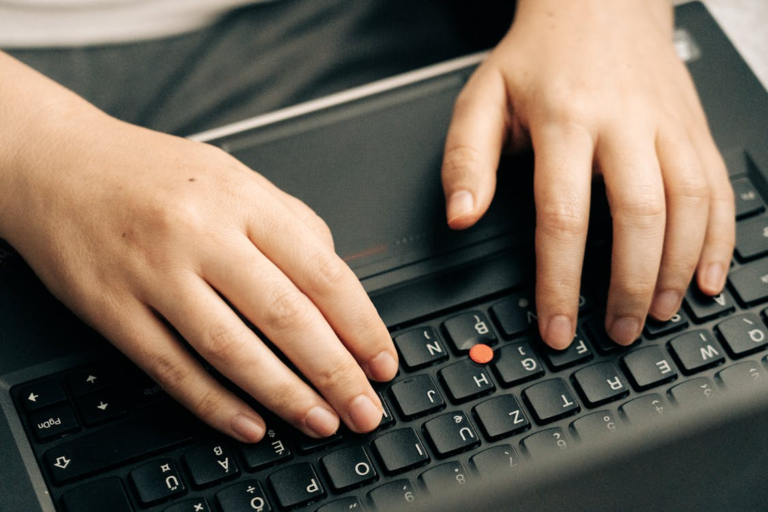 Graduate student typing on a laptop while reviewing scientific thesis revisions